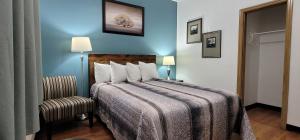 a hotel room with a bed and a chair at MacIver's Motel and Camp in Blind River