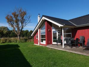 a red barn with chairs and a table in a yard at Grobenbrode Split-Wing House in Grossenbrode
