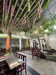 a patio with tables and chairs and trees and flowers at Hotel Song biển in Phan Thiet +11 photos