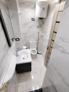 a white bathroom with a toilet and a sink at Portogolf elalamin in El Alamein +1 photo