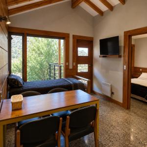 a room with a table and a bed and a tv at Refugio Cordillera Flora endógena Bosque Esclerófilo in San José de Maipo