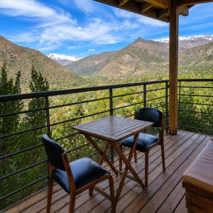 a table and chairs on a deck with mountains at Refugio Cordillera Flora endógena Bosque Esclerófilo in San José de Maipo