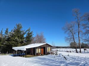 a small cabin with a snow covered roof in the snow at Paraíso Rustico 1 in Curacautín