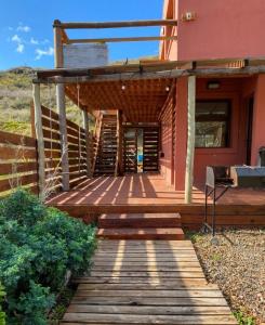 a wooden walkway leading to a house with a porch at Cabaña del Mirador 5 in Puerto Pirámides