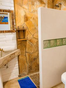 a bathroom with a stone wall and a refrigerator at Bananoz Surfhouse in Transito