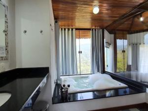 a bathroom with a bath tub with a large window at Pousada Bela Mauá in Itatiaia +57 photos