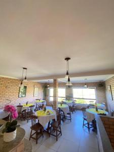 a dining room with tables and chairs and windows at HervaDoce in Rio das Ostras