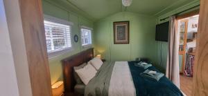 a small green bedroom with a bed and a window at Rameka Chalet in Takaka
