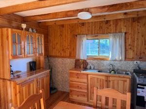 a kitchen with wooden cabinets and a sink and a window at Refugio Barbara - Coñaripe in Coñaripe +13 photos