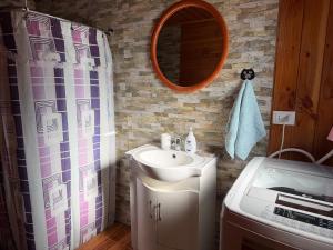 a bathroom with a sink and a shower curtain at Refugio Barbara - Coñaripe in Coñaripe