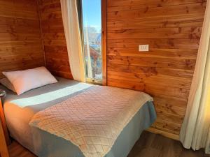 a small bed in a room with a window at Refugio Barbara - Coñaripe in Coñaripe