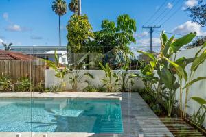 a swimming pool in a garden with plants at Solara Escape Mooloolaba - Luxe Pet-Friendly Home in Alexandra Headland