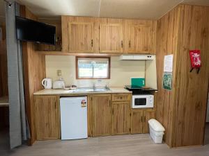 a small kitchen with wooden cabinets and a white refrigerator at Mansfield Lakeside Caravan Park in Mansfield
