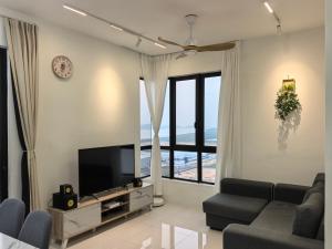 a living room with a couch and a flat screen tv at Batu Kawan Sunset Seaview Condo near Ikea & Design Village in Batu Kawan