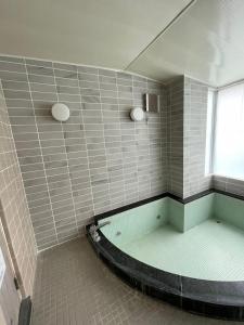 a tiled bathroom with a glass floor and a window at Momo Lodge Madarao in Iiyama