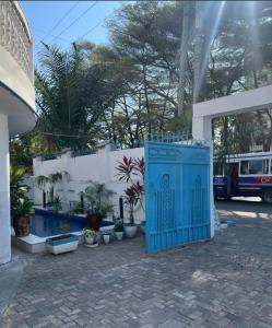 a blue gate in front of a building with potted plants at Arrabella Masaki in Dar es Salaam