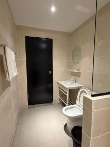 a bathroom with a black door and a toilet and a sink at The Velton Inn in Bintulu +30 photos
