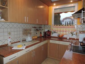 a kitchen with wooden cabinets and a sink and a window at Relax Apartman in Hajdúszoboszló