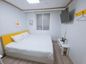 a bedroom with a white bed and a tv at G Hotel near Busan Station in Busan