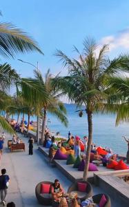 a group of people sitting on the beach with palm trees at LV Homestay in Nha Trang