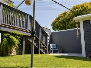 a staircase leading to a house with a lawn at Bach By The Beach in Mount Maunganui