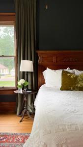 a bedroom with a bed with a lamp and a window at Spacious 4 BDR Historic Home in Heart of Sioux Center in Sioux Center