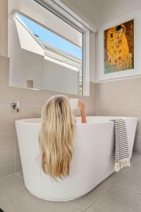 a woman sitting in a bath tub in a bathroom at Reflections Topaz Villa 3 in Picnic Bay