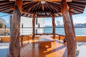 a wooden gazebo with a bench in front of the water at Yeosu Turtleship Pension in Yeosu