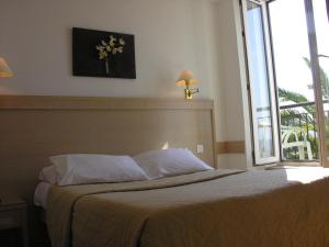 a bedroom with a bed with a large window at Hôtel La Flore in Villefranche-sur-Mer