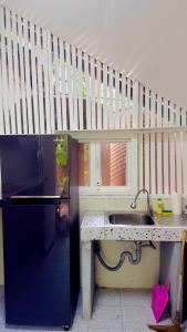 a kitchen with a sink and a refrigerator under a stairs at Nomad house in Hin Kong in Ko Phangan