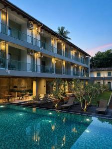 a hotel with a swimming pool in front of a building at Grids by Epic Collection in Unawatuna