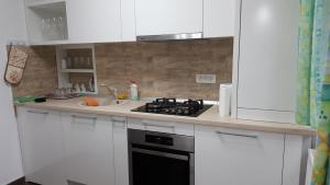 a white kitchen with a stove and a sink at Sweet Home in Timişoara