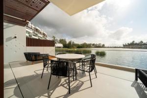 a patio with a table and chairs next to the water at Laguna luxury apartment - Bang Tao - lake view in Bang Tao Beach