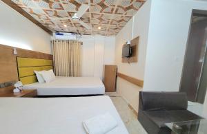 a hotel room with two beds and a chair at Hotel The One Point, Uttara in Bāiljuri +9 photos