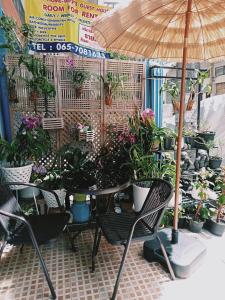 a table and chairs with potted plants and an umbrella at Happy Home Guest House in Ban Phe