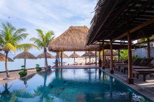 a resort swimming pool with umbrellas and the ocean at Pemedal Beach Resort in Nusa Lembongan