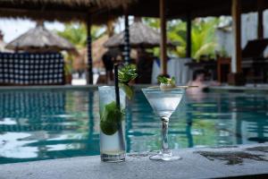 a margarita and a drink on a table next to a pool at Pemedal Beach Resort in Nusa Lembongan