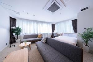 a living room with a bed and a couch in a room at Olympic Inn Azabu in Tokyo