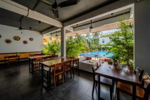 a dining room with tables and chairs and a pool at Onederz Kampot in Kampot