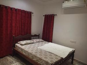a bedroom with a bed with red curtains at Casa de Victoria in Alleppey