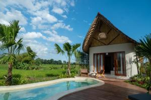 a villa with a swimming pool and a house at Bamboo Layang Ubud in Ubud