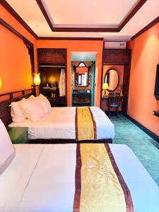 two beds in a room with orange walls at Spatel d'Annam - Imperial Boutique Spa & Hotel in Hue
