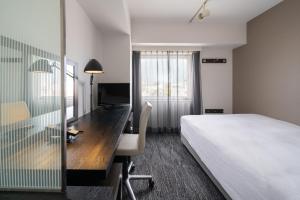 a hotel room with a bed and a desk with a computer at Hotel Vista Sapporo Odori in Sapporo