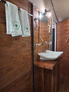 a bathroom with a sink and towels on a wooden wall at Wilpattu Wilderness Camping in Wilpattu