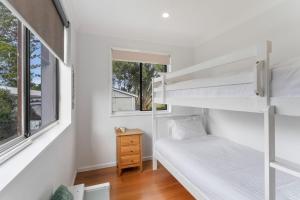 a bedroom with two bunk beds and a window at Blue Summer House in Long Jetty
