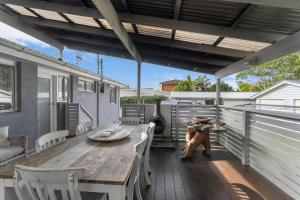 a teddy bear sitting on a deck with a wooden table at Blue Summer House in Long Jetty +14 photos