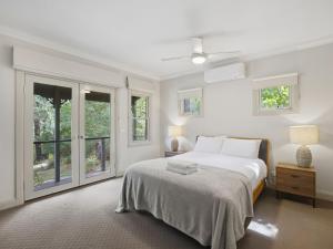 a white bedroom with a bed and windows at Woodbine Lodge in Marysville