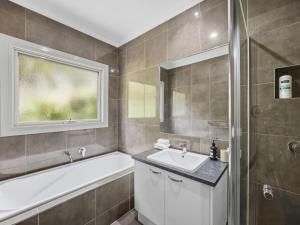 a bathroom with a tub and a sink and a window at Woodbine Lodge in Marysville +4 photos