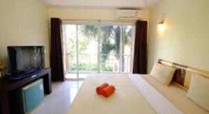 a bedroom with a bed with a tv and a window at The Room Hotel in Ban Nong Puk