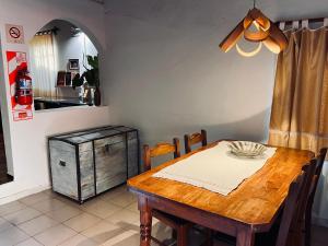a dining room with a wooden table and a kitchen at Casa Toia - Cerca del río, cerca de vos in Posadas